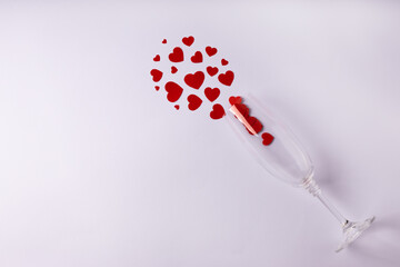 One glass with red hearts on white background. Valentine's Day, February 14, love concept. Flat lay, top view, copy space.