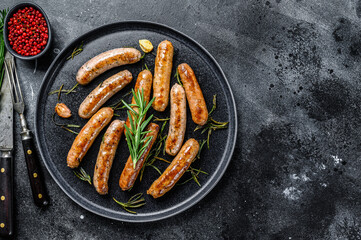 Grilled sausages with rosemary herbs, beef and pork meat. Black background. Top view. Copy space - obrazy, fototapety, plakaty