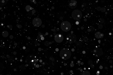 Bokeh of white snow on a black background. Falling snowflakes on night sky background, isolated for...