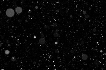 Bokeh of white snow on a black background. Falling snowflakes on night sky background, isolated for...