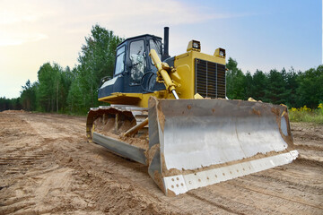 Dozer during clearing forest for construction new road . Yellow Bulldozer at forestry work Earth-moving equipment at road work, land clearing, grading, pool excavation, utility trenching © MaxSafaniuk