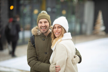 Embracing couple looking at camera with smiles in winter park.