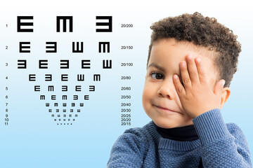 Little afro american kid having vision review with chart.
