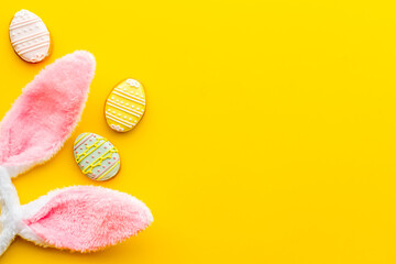 Top view of Easter bunny ears with eggs cookies, space for text