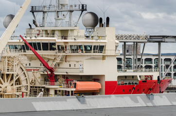 RED SHIP WITH A HELIPAD - Pipe laying vessel moored in seaport

