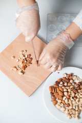 Girl's hands chop hazelnuts for filling in homemade chocolate