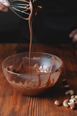 Picture of whisk with chocolate for cake preparation, sweet cake glaze home made process with cocoa melt together to create a glaze for sweet cake and chocolate, close up
