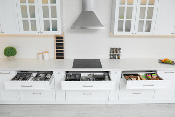 Open drawers with different utensils in kitchen
