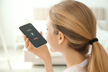 Young woman using voice search on smartphone indoors