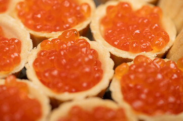 Tartlets with salmon caviar on a platter. Close-up, selective focus.