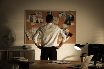 Detective looking at evidence board in office