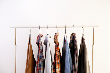 Men's hip clothing store sale concept. Row of different stylish male clothes hanging on rack in...