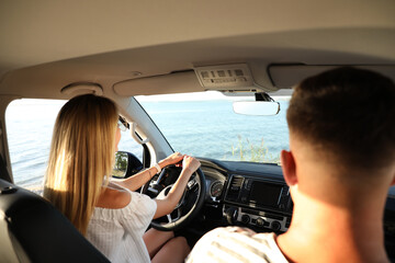 Couple in car near sea on sunny day. Summer trip