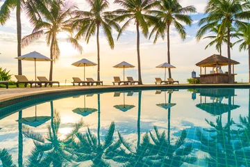 Fotobehang Mooie luxe parasol en stoel rond buitenzwembad in hotel en resort met kokospalm op zonsondergang of zonsopgang © topntp