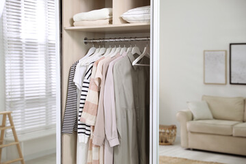 Wardrobe closet with different stylish clothes in room, closeup