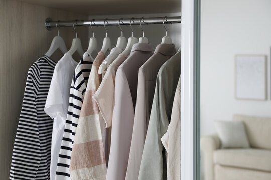 Wardrobe closet with different stylish clothes in room, closeup