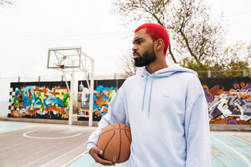 Bearded african american guy standing with basketball at playground