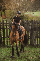 woman riding her brown horse with black mane dressed in black with a helmet