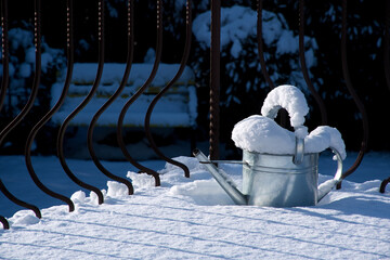 Gießkanne mit Schnee bedeckt, Gartenarbeit im Winter