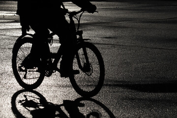 Obraz premium Black silhouette of a cyclist on the wet road. Person riding a bicycle, cycling concept, dramatic atmosphere