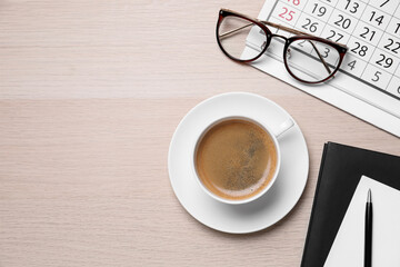 Flat lay composition with coffee and calendar on wooden table. Space for text
