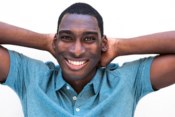 young black man smiling with hands behind head against isolated white background