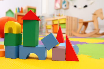 Wooden castle made of colorful blocks on carpet in playroom. Interior design