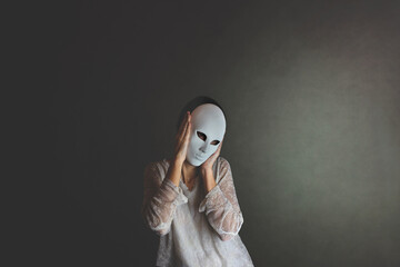 woman covers her face with a mask to protect herself, concept of loneliness and introspection..