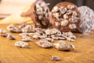Sweet, ice cream cone filled with chocolate and cream with chocolate flakes, on rustic wood, selective focus.