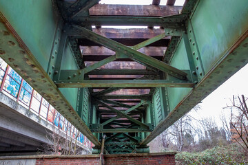 Alte Eisenbahnbrücke aus Stahl mit gemauertem Widerlager und Durchsicht auf die massiven Holzschwellen und Gleisprofile