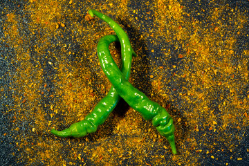 Green chili pepper and seasoning on a black background, tasty food