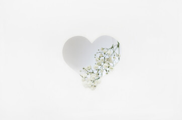 paper cut greeting card with valentine's day. a white heart is cut out of paper with Gypsophila flowers on a white background. gentle postcard to the day of the wedding