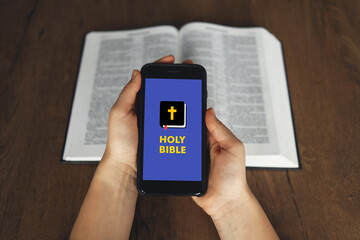 Woman hand hold and touch screen smart phone,cellphone in church over blurred bible holy and age...