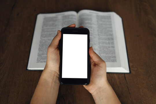 Woman hand hold and touch screen smart phone,cellphone in church over blurred bible holy and age book