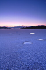 Fototapeta na wymiar 湖面を覆った氷に点在するアイスバブル。美しい夜明けの空のグラデーション。氷点下の冬の朝の風景。屈斜路湖、阿寒摩周国立公園、北海道、日本。