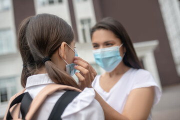 Mom correcting protective mask on her daughter