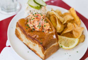 A cheese, prawn, seafood and tomato brioche sandwich, served with crisps and a wedge of lemon.