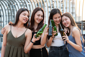 Group of young beautiful Asian girl gang best friends having party together at rooftop and clinking bottles together.Girls toasting bottles feeling happy enjoy, fun with smile face.