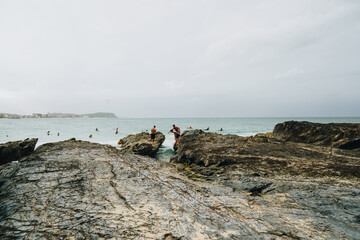 Boys jumping between two rocks at Currumbin