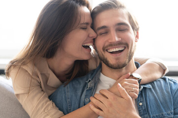 Happy couple or marriage hugging and enjoying in a couch at home.