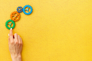 Teamwork concept. Hand connecting gears into puzzle - symbol of working mechanism
