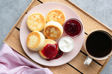 Breakfast cottage cheese fritters with raspberry jam, sour cream and black coffee