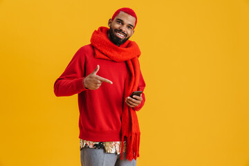 Happy african american guy holding and pointing finger at mobile phone