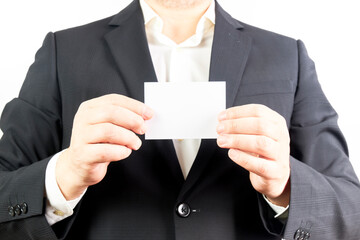 Businessman in black suit holding a white card with copy space