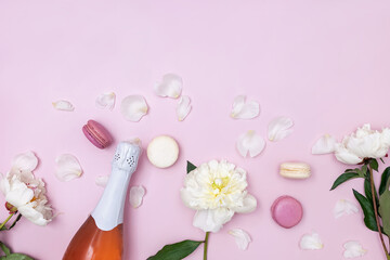 Spring composition with rose sparkling wine, white peonies and macarons