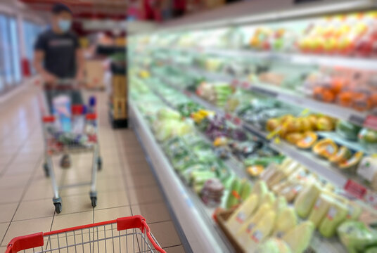 Abstract blur in supermarket with shopper wearing face fask.