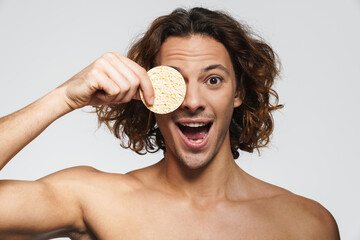 Surprised shirtless handsome guy posing with cosmetic sponge