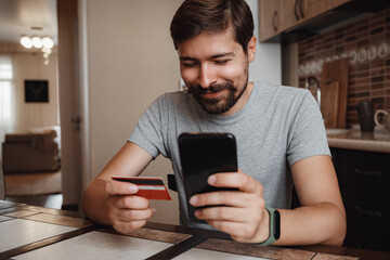 hipster young man shopping online with credit card using smart phone at home.