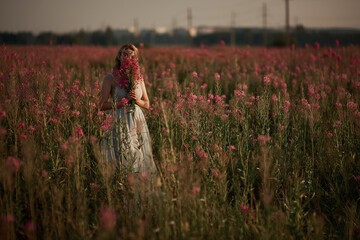 Young beautiful girl with a bouquet of flowers in her hands at sunset.