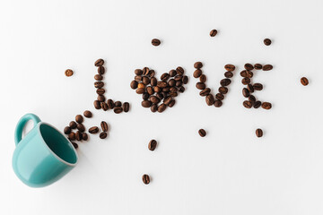 Phrase Love made of coffee beans spilled out from blue cup on white table. flat lay. creative photo of coffee. suitable for Valentine day, cafe, restaurants and wallpapers.